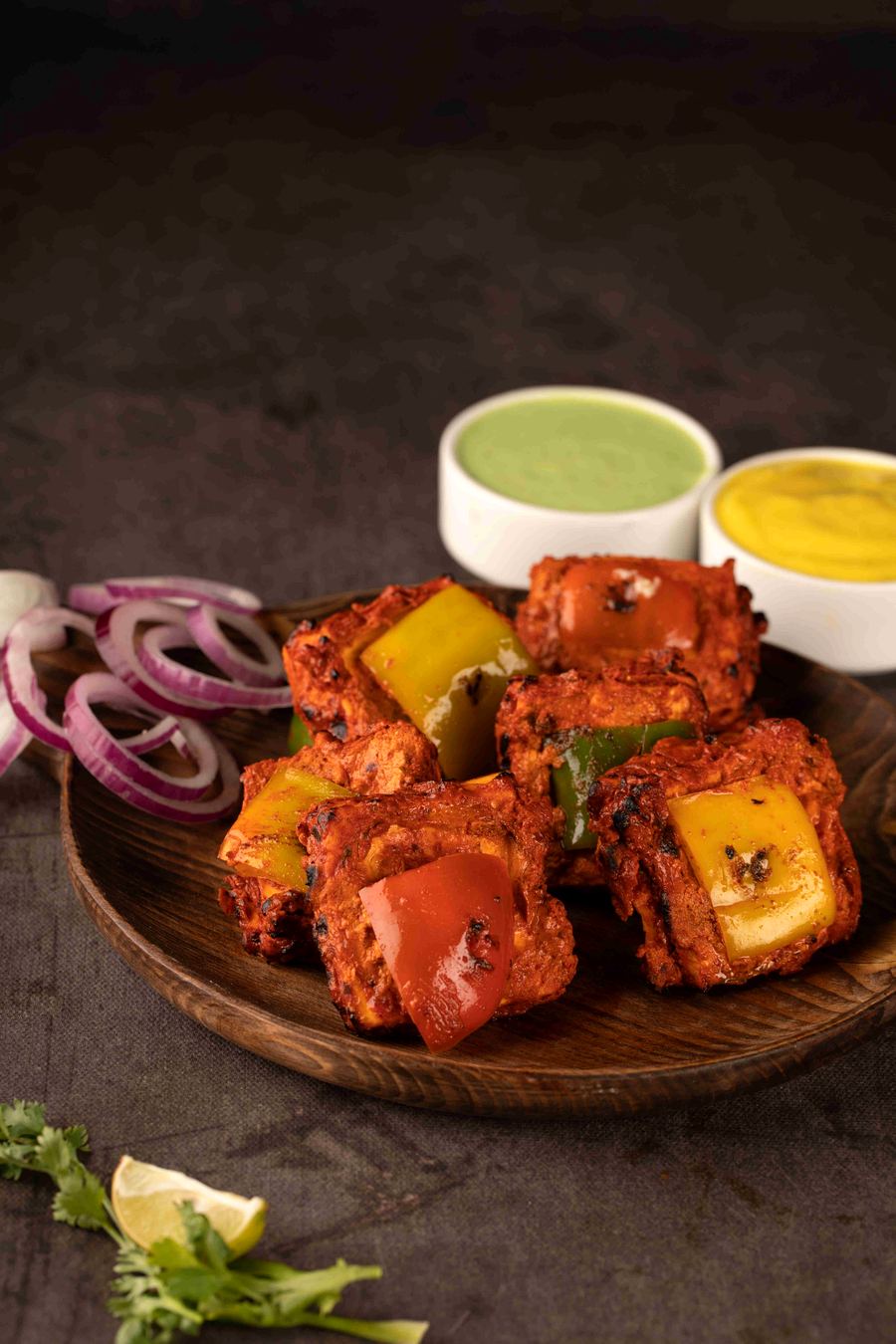 Tandoori paneer tikka with capsicum on a wooden board